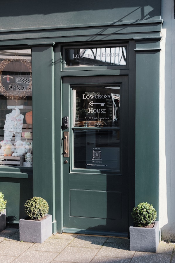 Una puerta verde con un letrero que dice 'LOWER CROSS HOUSE GUEST BEDROOMS' y una dirección web.