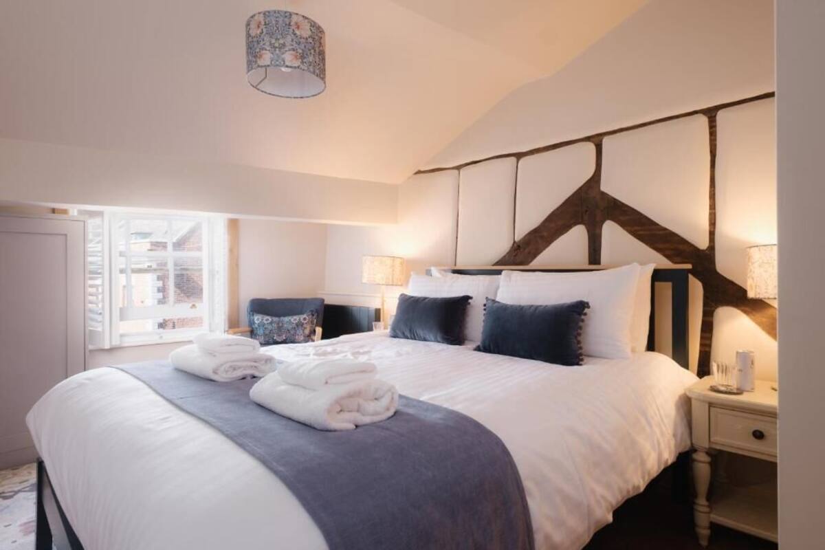 A bedroom with a large bed, a wooden headboard, bedside lamps, and a window with a view.