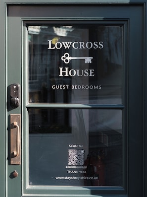 Una puerta con un ventanal que muestra 'Lowcross House Guest Bedrooms' y un código QR para 'Scan M.I.'