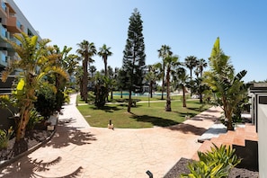 A paved walkway with palm trees and a pool in the background. - AlmeriaSuite Palm Beach Golf & Pool 7002 (El Ejido)