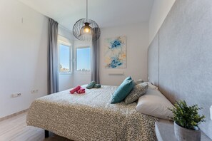 A bedroom with a bed, a window, a painting, and a plant. - AlmeriaSuite Palm Beach Golf & Pool 7002 (El Ejido)