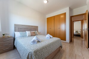 A bedroom with a bed, wooden wardrobe, bedside table, and a nightstand. - AlmeriaSuite Palm Beach Golf & Pool 7302 (El Ejido)
