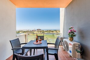 A balcony with a table, chairs, a fan, and a flower vase. - AlmeriaSuite Palm Beach Golf & Pool 7302 (El Ejido)