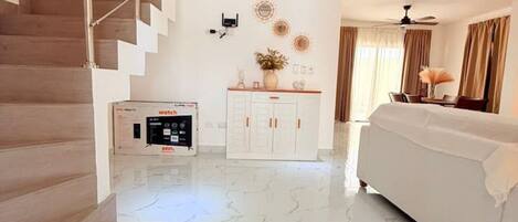 A hotel room with a marble floor, a bed, a desk, a wardrobe, and a staircase.
