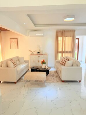 A modern living room with two sofas, a coffee table, and a decorative cabinet. - NEW Pool Villa | Downtown | Electricity Included (Punta Cana)