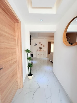 A hallway with a wooden door, a potted plant, a white cabinet, and a mirror on the wall. - NEW Pool Villa | Downtown | Electricity Included (Punta Cana)