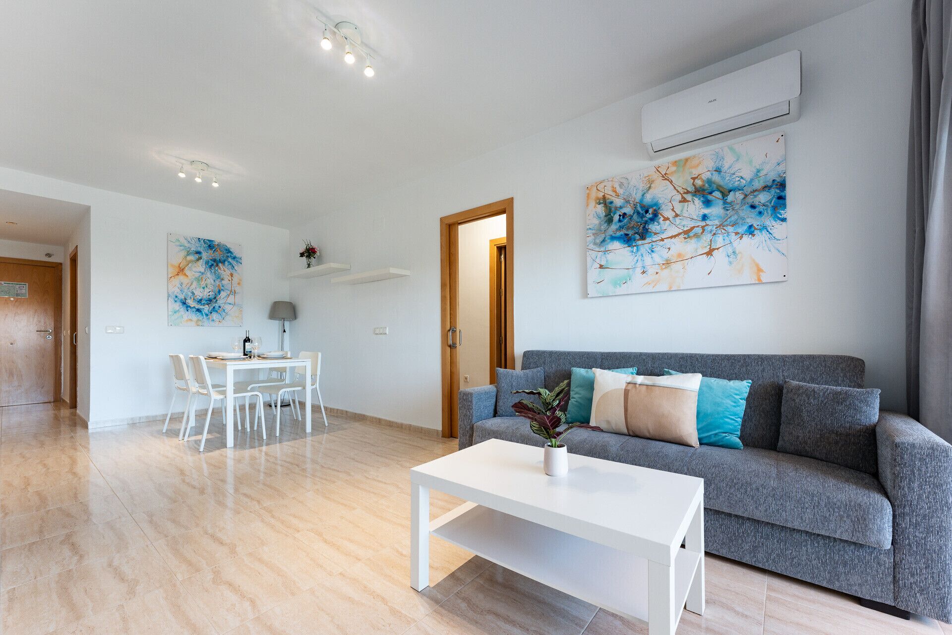 Un salon moderne avec un canapé gris, une table basse blanche et un coin repas comprenant une table et des chaises.
