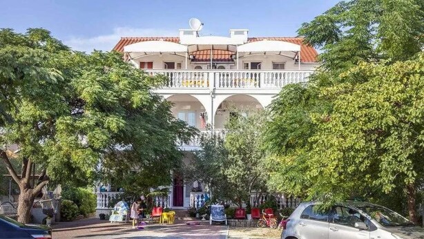 Um edifício com um pátio central, uma varanda e um carro estacionado na frente.
