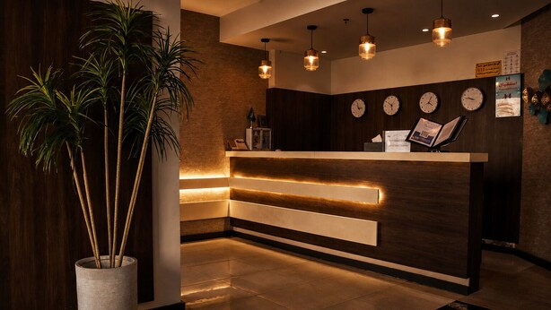 A reception desk with a wooden finish, multiple clocks, and a potted plant. - HMM Serviced Apartments Taybah Jeddah (Jeddah)
