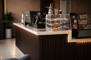 A reception desk with a coffee machine, a snack display, and a coffee dispenser. - HMM Serviced Apartments Taybah Jeddah (Jeddah)