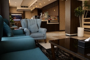 A modern lobby with a seating area, a reception desk, and a television screen. - HMM Serviced Apartments Taybah Jeddah (Jeddah)