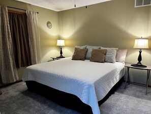 A neatly made bed with a white duvet, two bedside lamps, and a small table with a lamp.