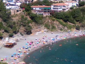 Eine Küstenlandschaft mit Strand, Gebäuden und viel Grün.