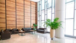 A spacious lobby with a high ceiling, large windows, and a central seating area with sofas and tables. - Solaris Premier 1BR | Osu • Pool • Gym (Accra)