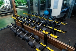 Ein Fitnessraum mit mehreren Reihen Kurzhanteln, Gymbällen und Bänken.