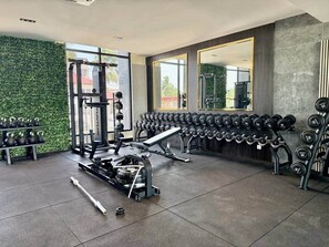A gym with weightlifting equipment, dumbbells, and a treadmill. - Harmonia Studio | Airport City • Pool • Fast WiFi (Accra)