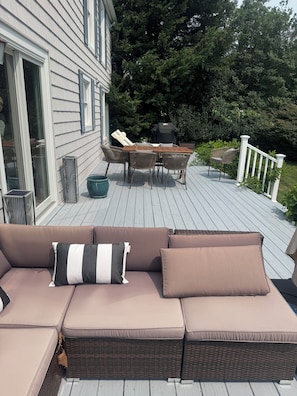 Une terrasse avec un canapé, une table, des chaises et un barbecue.