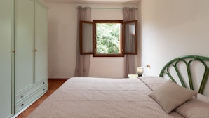 Une chambre à coucher comprenant un lit, une armoire, une fenêtre avec des rideaux, une lampe de chevet et une tête de lit verte.