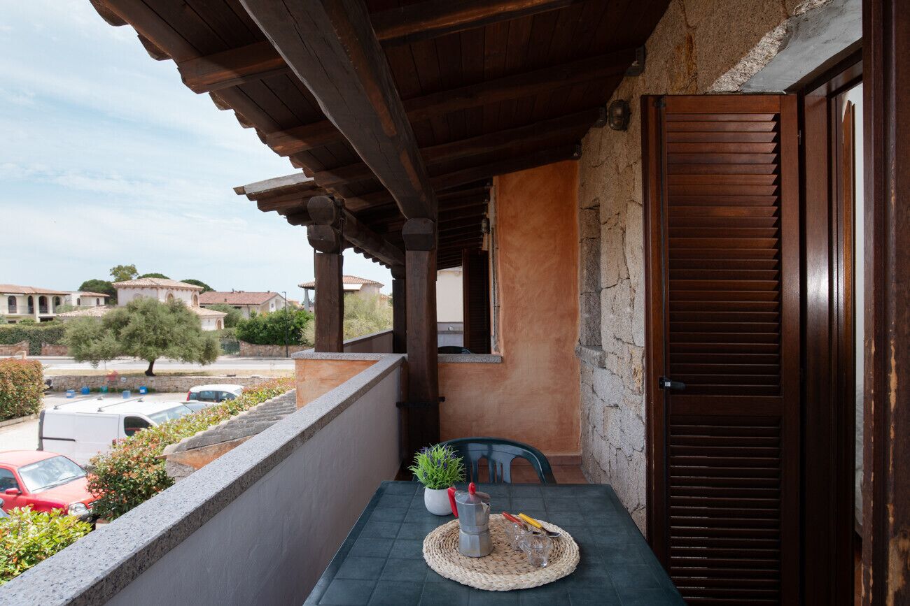 Ein Balkon mit Tisch, Blumentopf und einer Tür.