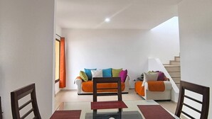 A living room with a sofa set, a dining table, and a staircase. - Vista Central Park Caucel3 Habitaciones (Caucel)