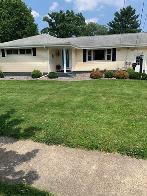 A single-story house with a front porch, a small front yard, and a driveway. - Splash and Stay. Enjoy the backyard oasis after a day in the sun (Norwalk)