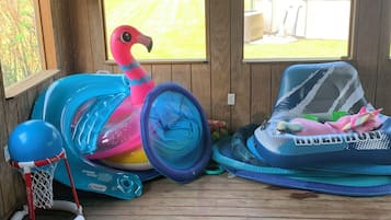 En överbyggd träveranda med uppblåsbara leksaker, bland annat en flamingo och en basketkorg.