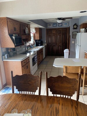 A kitchen with wooden cabinets, a microwave, a coffee maker, and a dining area with a table and chairs.