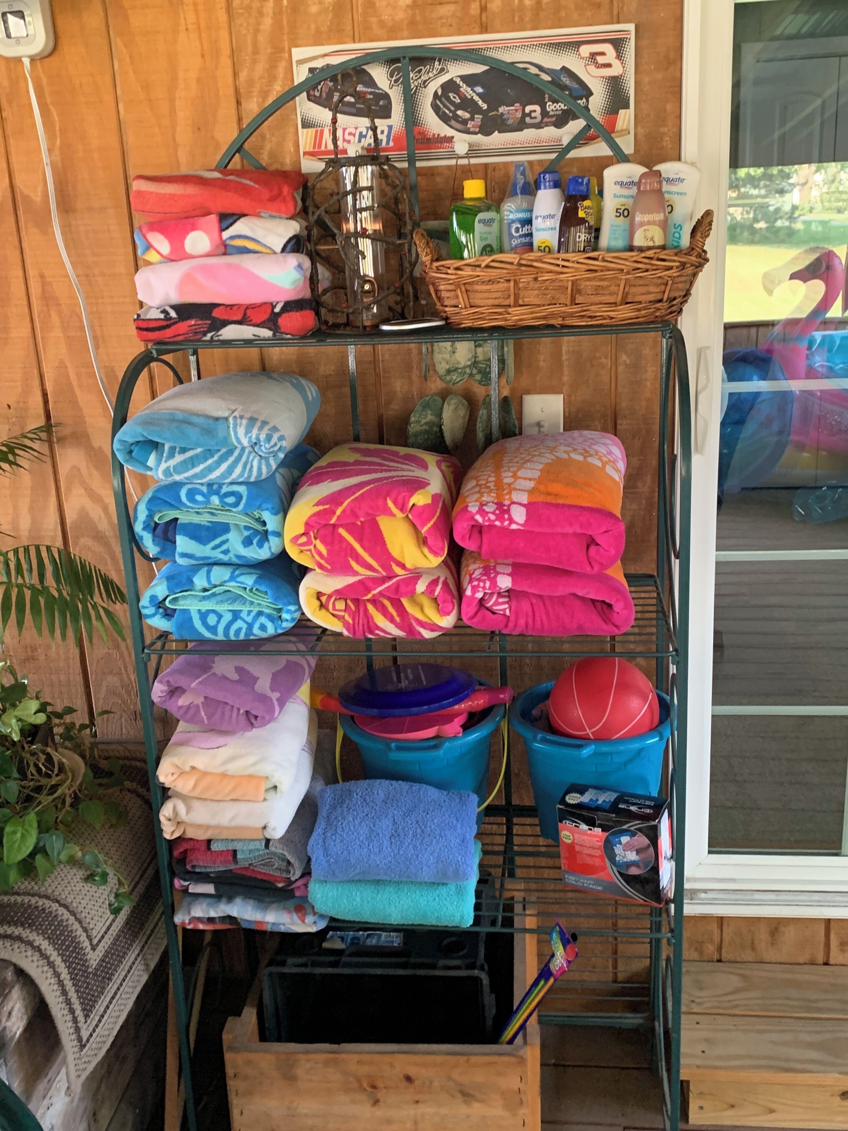 A shelf with neatly folded towels and a basket with toiletries.