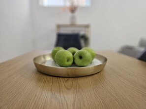 Et rundt træbord med en tallerken grønne æbler.