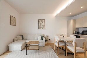 Una sala moderna con un sofá seccional, una mesa de centro y un comedor con sillas.