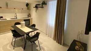 Une cuisine moderne avec un coin repas, un téléviseur à écran plat et une grande fenêtre avec des rideaux.