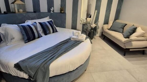 Une chambre moderne avec un lit rond, un canapé, une fenêtre et un mur à rayures.