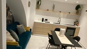 Une cuisine moderne avec un coin repas, comprenant un canapé, une table, des chaises et un îlot de cuisine doté d’un évier et d’un plan de travail.