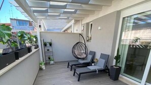 Un balcon avec un plancher en bois, un fauteuil suspendu et des plantes en pot.