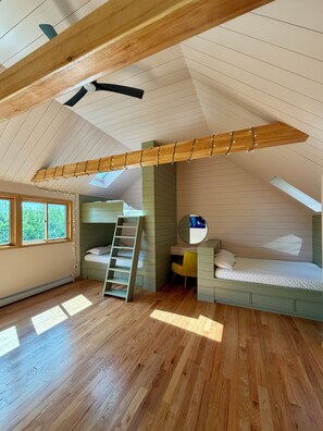 Un dormitorio tipo loft con literas, un escritorio y una silla.
