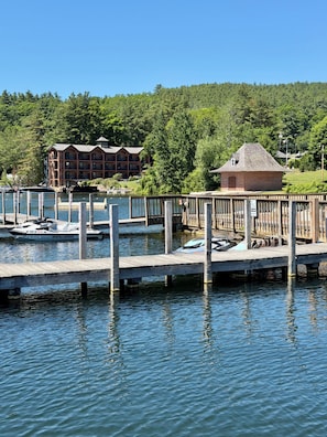 Une propriété située au bord de l’eau, dotée d’un quai, d’un petit bâtiment en briques et, au fond, d’un chalet à plusieurs étages.