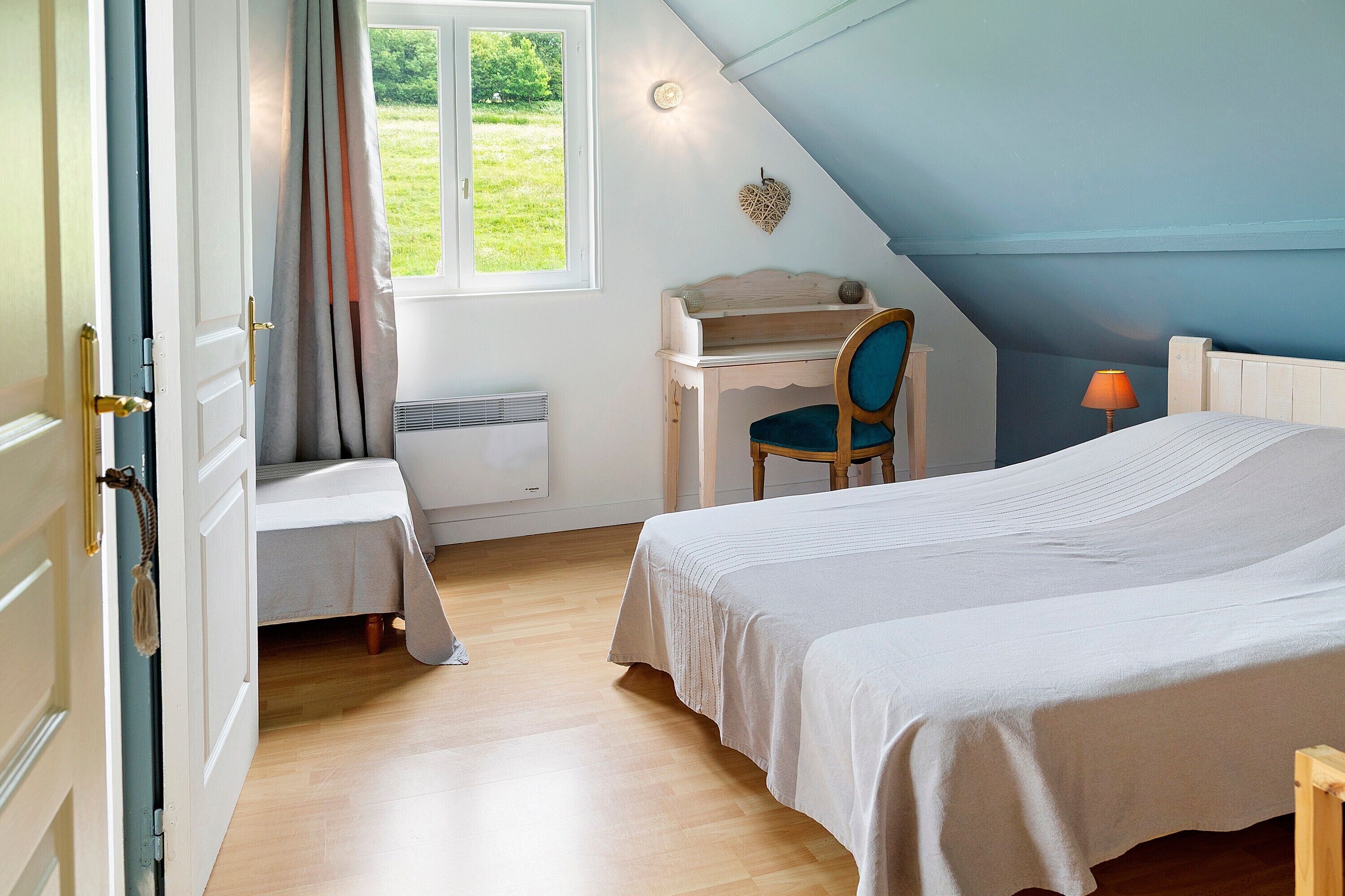 Ein Schlafzimmer mit Bett, Schreibtisch, Stuhl, Fenster und Lampe.