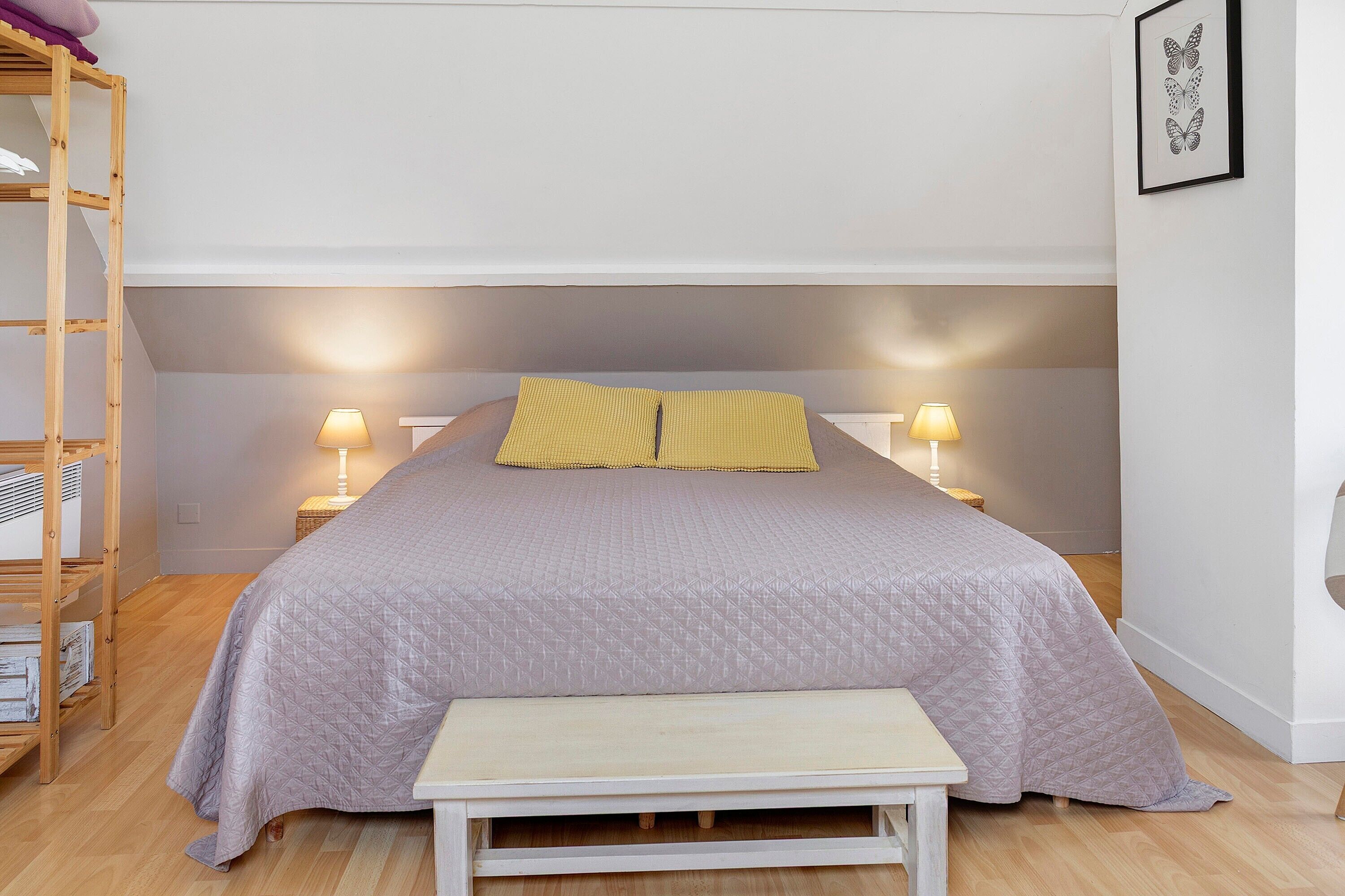 Une chambre à coucher avec un lit, des lampes de chevet, un banc et une échelle en bois.