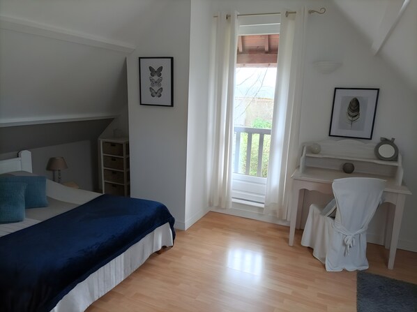 Une chambre Ă coucher avec un lit, un bureau, une chaise, une fenĂȘtre avec des rideaux et un tableau au mur.