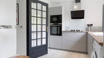Una cocina moderna con una puerta negra, un microondas, un horno y una lavadora.