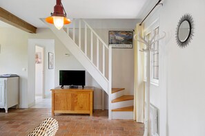 Eine Treppe mit weißen Geländern, eine Holzkommode mit einem Fernseher und ein wandmontierter Spiegel.
