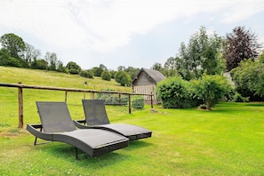 A grassy area with two reclining chairs and a wooden structure in the background. - Gîte La Cour Du Four - Deauville with Private Terrace, Garden, and Wi-Fi (Saint-Hymer)