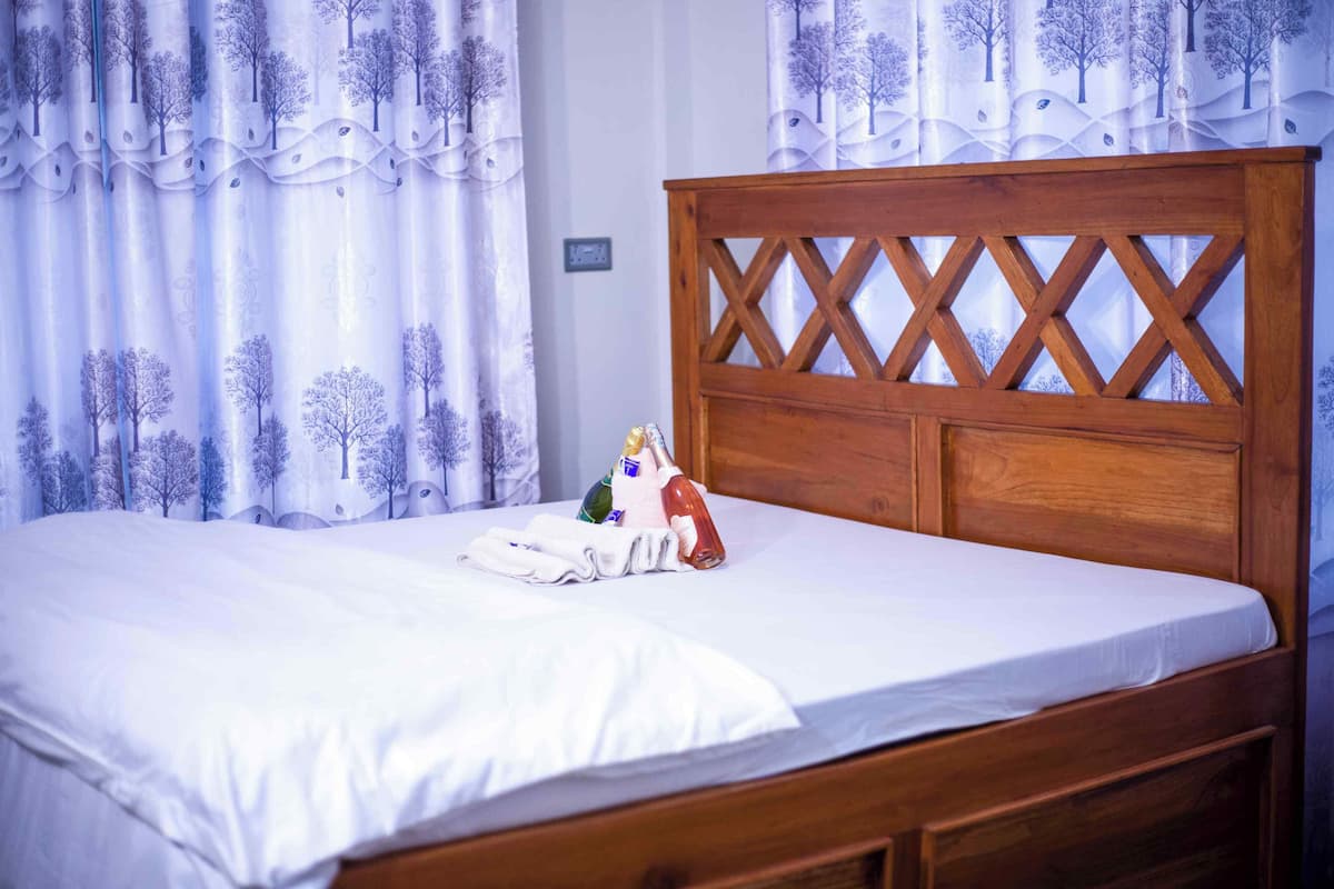 Un lit avec une tête de lit en bois, une literie blanche et un petit objet décoratif posé sur le lit.