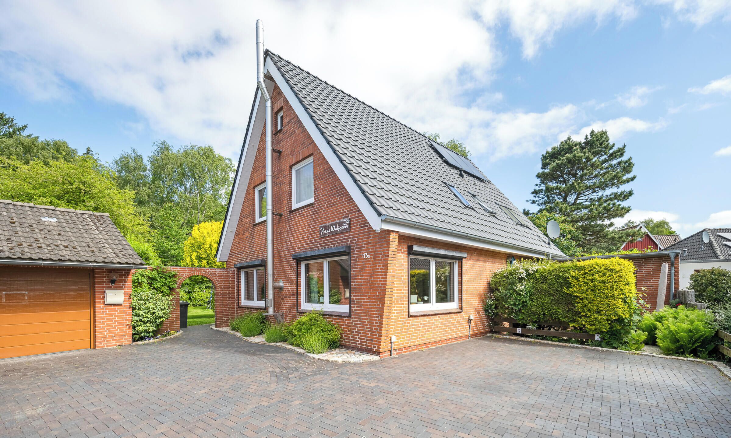 A single-story brick house with a sloped roof, a garage, and a paved driveway.