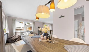 Uma sala de estar moderna com uma mesa de jantar de madeira, móveis brancos e uma lareira.