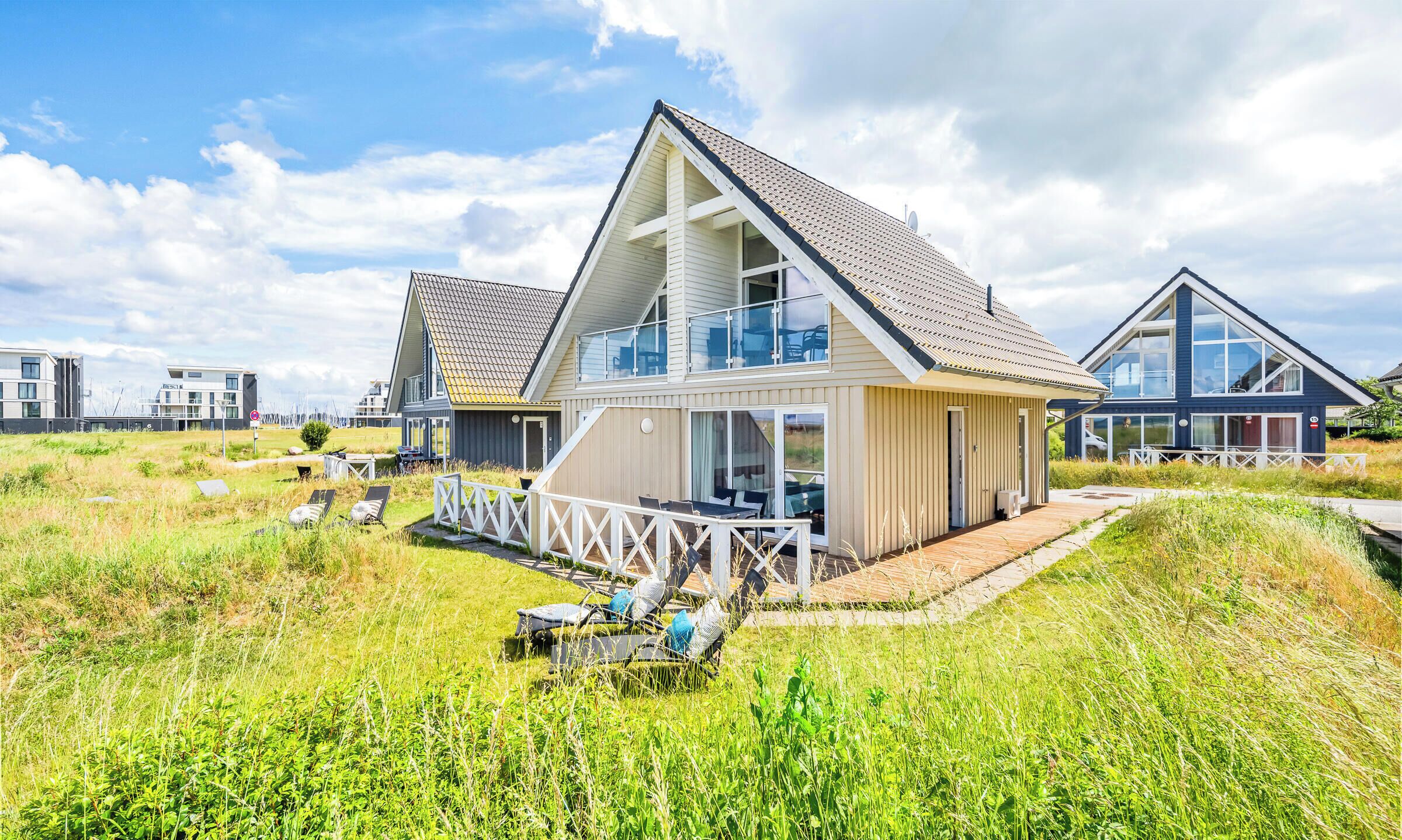Ett modernt strandhus med en balkong, en terrass och utsikt över havet.