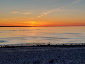 Ein Strand mit Sonnenuntergang über dem Wasser.
