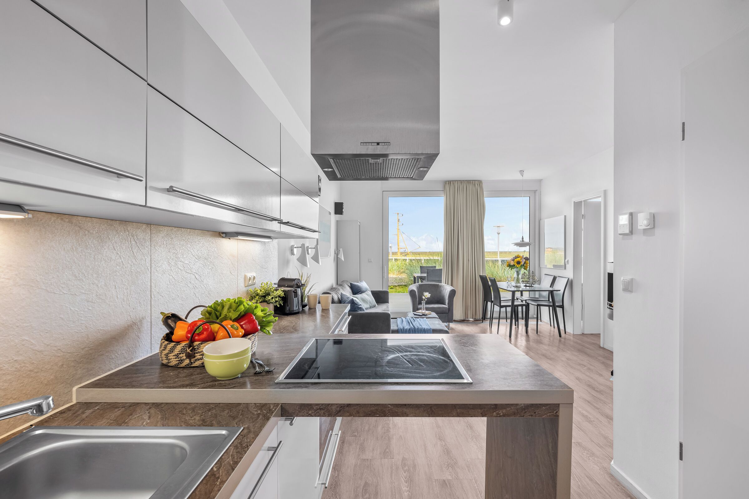 A modern kitchen with a central island, stainless steel appliances, and a view to an outdoor dining area.