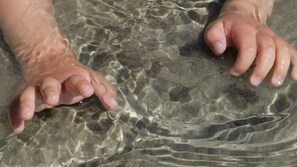 Nahaufnahme von Händen, die in klares Wasser mit sichtbarem Sediment getaucht sind.