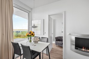 Ein moderner Essbereich mit einem weißen Tisch, schwarzen Stühlen und einem Blumenstrauß.